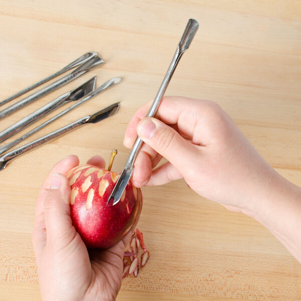 A hand using a Town stainless steel garnishing tool to peel an apple.