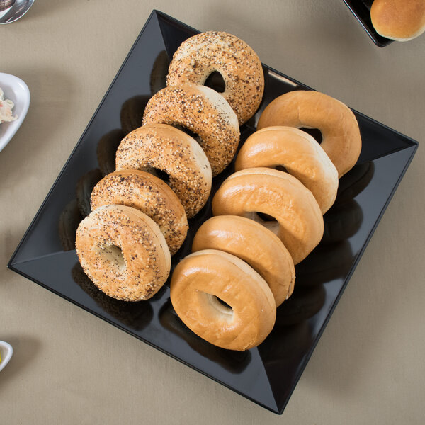 A black square melamine plate with bagels on it.