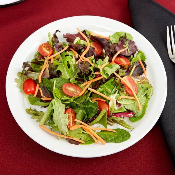 A Tuxton Colorado narrow rim white china plate with a salad of lettuce, tomatoes, and carrots.
