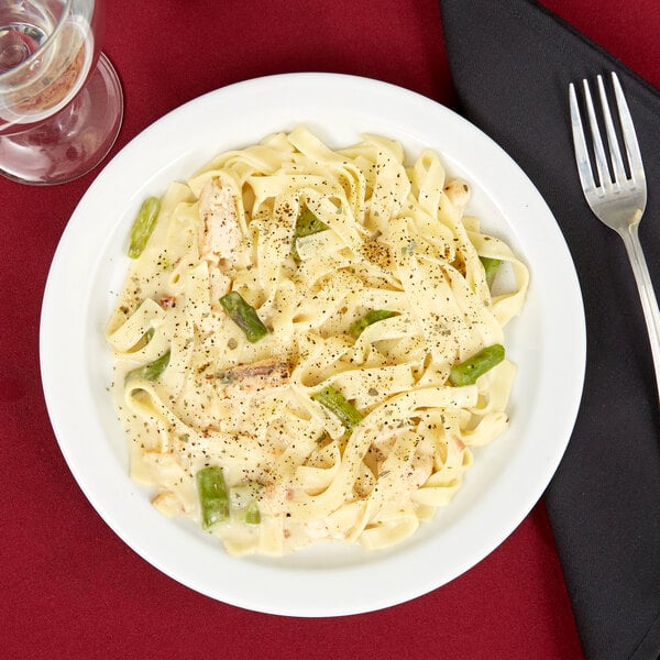 A Tuxton Colorado bright white narrow rim china plate with pasta and vegetables on it.