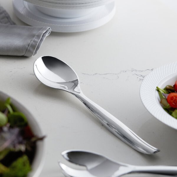 A silver spoon next to a bowl of salad.