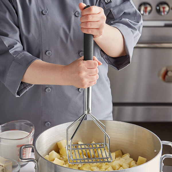 A person using a Thunder Group potato masher to mash potatoes in a pot.