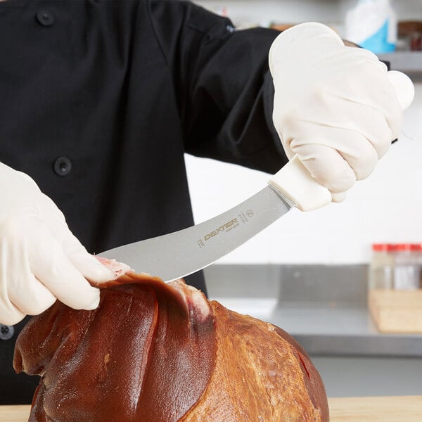 A person using a Dexter-Russell beef skinning knife to cut meat on a counter.