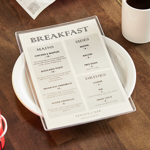 A clear heat sealed menu cover with a breakfast menu inside on a table in a brunch café.
