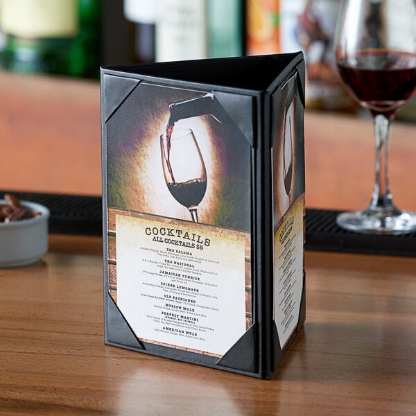 A Menu Solutions triple panel table tent with a glass of wine on a table.