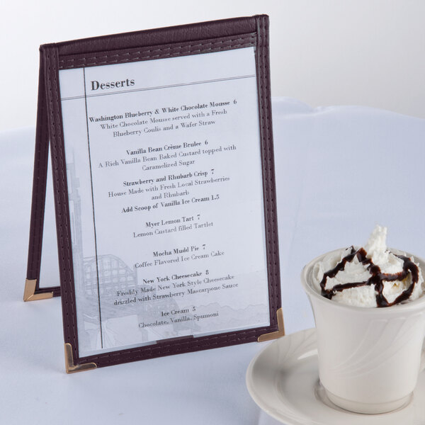 A Menu Solutions burgundy sewn edge table tent on a table with a cup of ice cream.