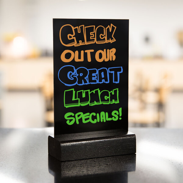 A black Menu Solutions wet erase sign board with colorful writing on it.