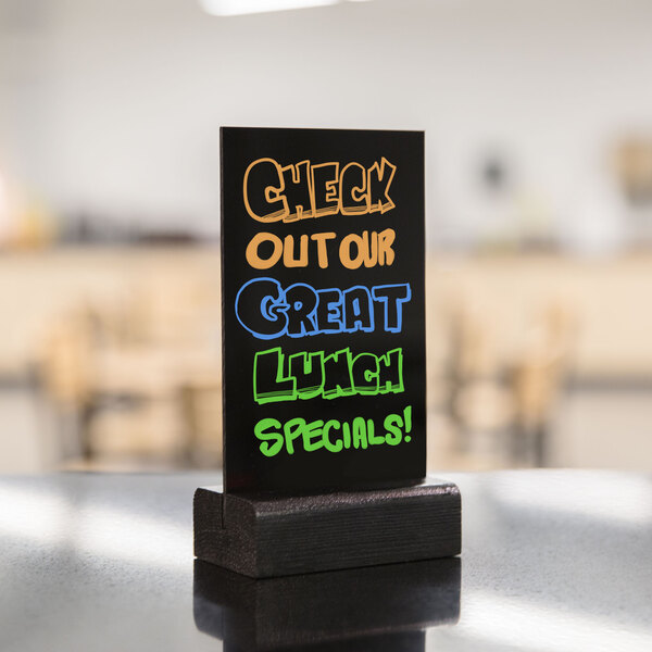 A black Menu Solutions table sign with colorful writing on it.