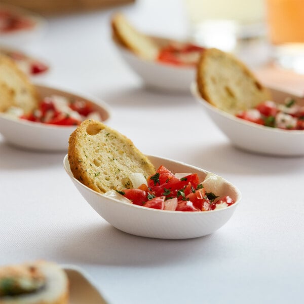 A table with a group of EcoChoice compostable appetizer bowls filled with food, including a bowl with bread and tomatoes.
