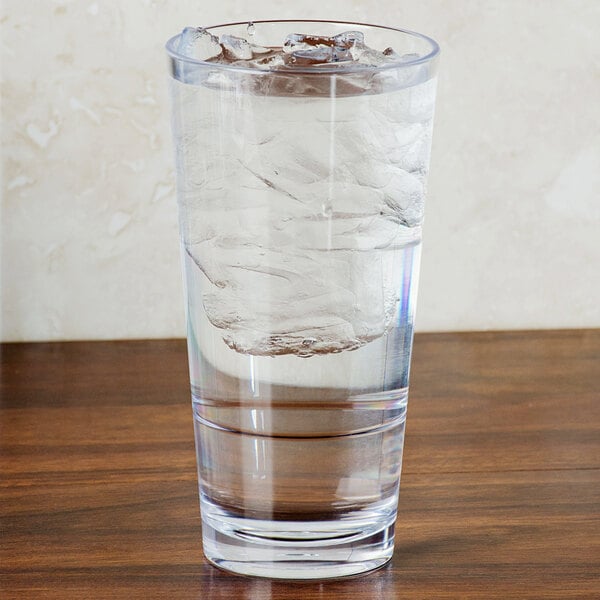 A GET stackable plastic mixing glass filled with ice water on a table.