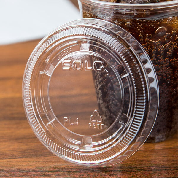 A Solo clear plastic lid on a plastic cup with brown soda.