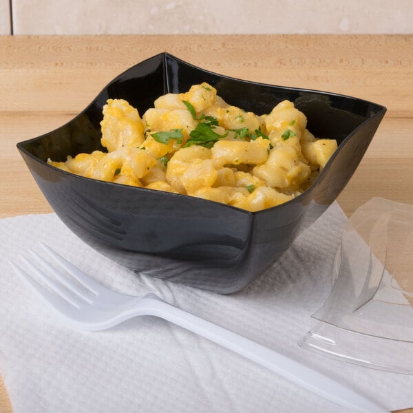 A Fineline black plastic bowl filled with macaroni and cheese with a white plastic spoon.