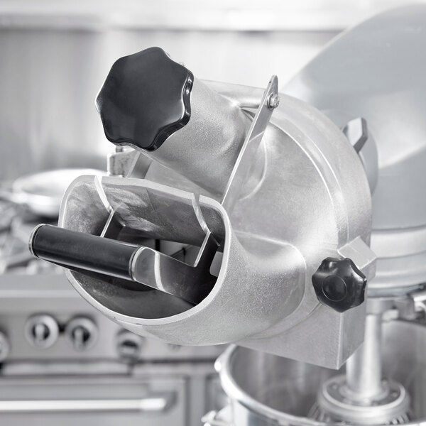 A close-up of a black and silver Vollrath slicer attachment.