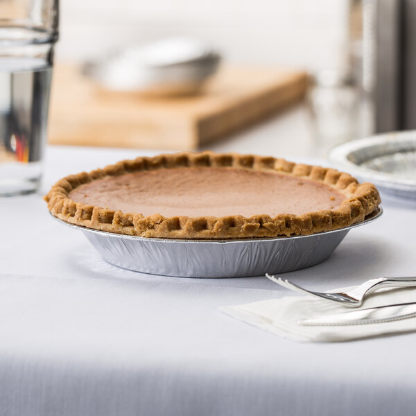 A Baker's Mark deep foil pie pan with a pie in it on a table.