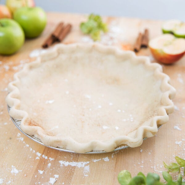 A Baker's Mark aluminum pie pan with a pie crust and apples on a table.