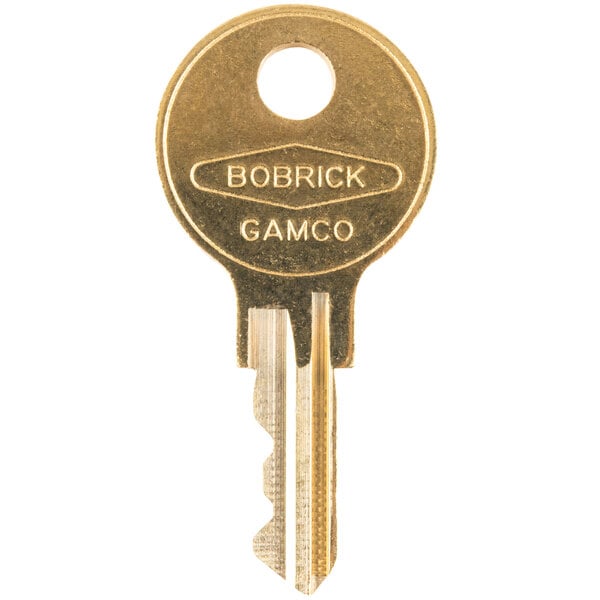 A close-up of a gold Bobrick cabinet door key with the words "Bobrick" and "Gamo" on it.