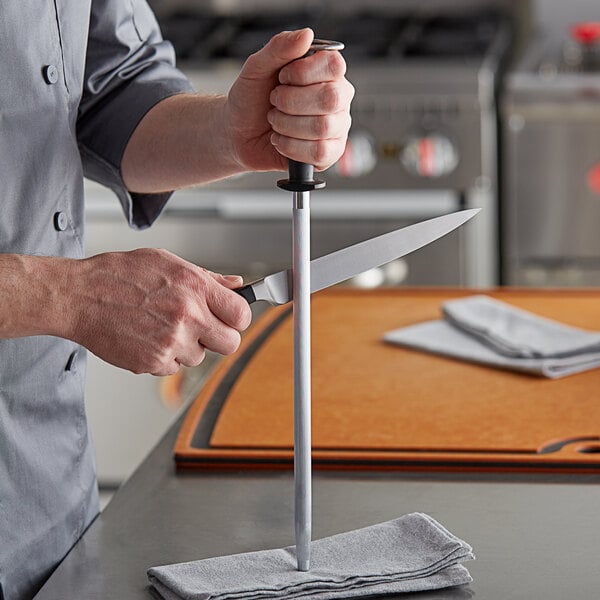 A man using a Dexter-Russell knife sharpening steel on a knife.