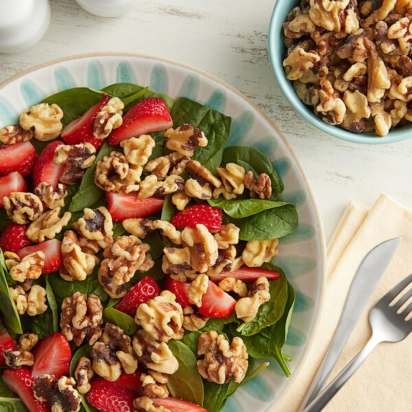 A plate of spinach salad with strawberries and walnuts.