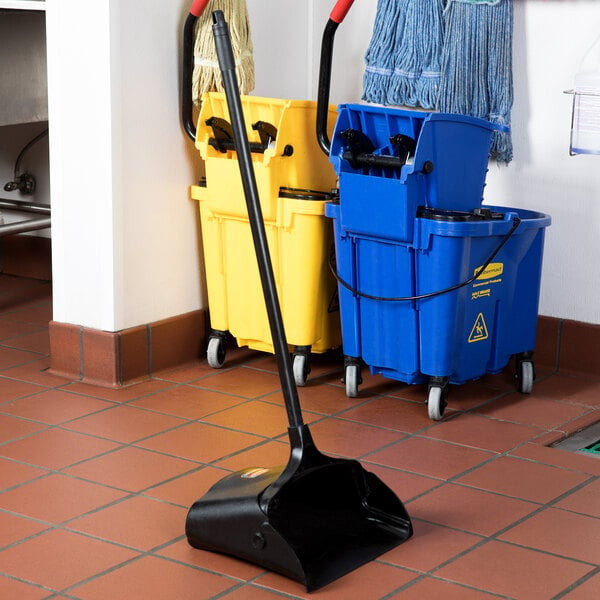 A Rubbermaid Lobby Pro plastic upright dust pan with a mop and bucket on a tile floor.