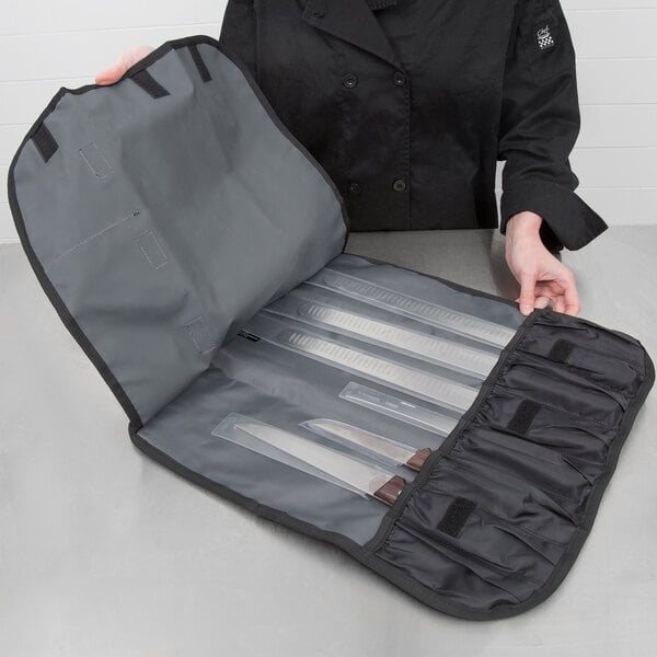 A woman in a black coat holding a Mercer Culinary black knife roll.
