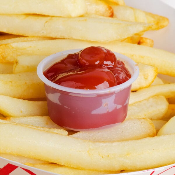 A Solo translucent polystyrene souffle cup of ketchup on french fries.