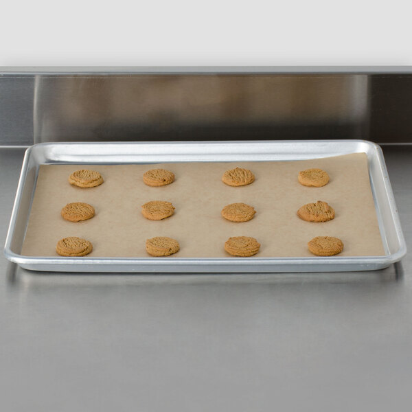 A Bagcraft Packaging parchment paper pan liner on a baking sheet with cookies.