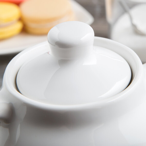 A close up of a Tuxton white china teapot lid on a white teapot.