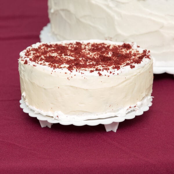 A Wilton scalloped edge cake separator plate with a red velvet cake on top.