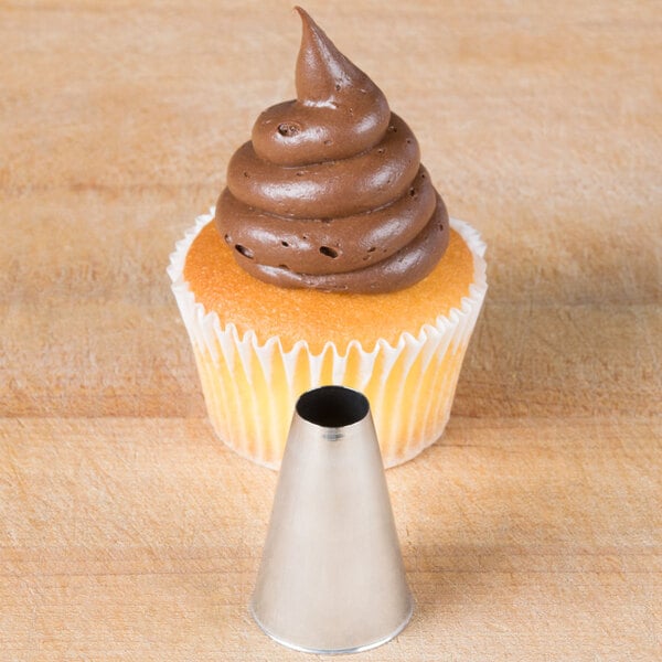 A cupcake with chocolate frosting piped on top using an Ateco plain metal piping tip.