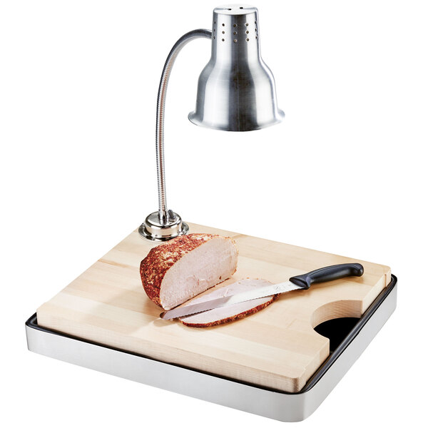 A Cal-Mil stainless steel carving station with a maple cutting board, knife, and heat lamp on a table.