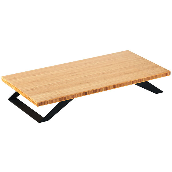 A Cal-Mil bamboo stair-step riser on a wooden table with black legs.