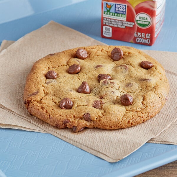 A chocolate chip cookie on a napkin with a box of Hershey's milk chocolate chips.