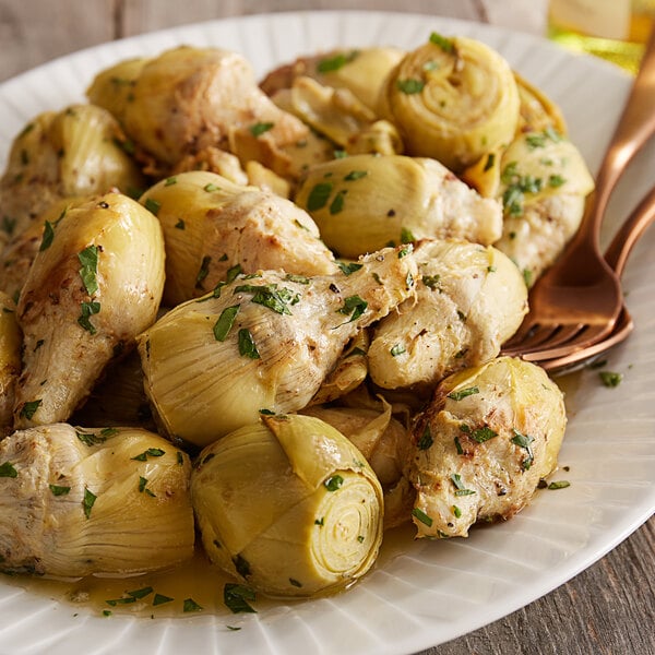 A plate of whole artichoke hearts with herbs on a white background.