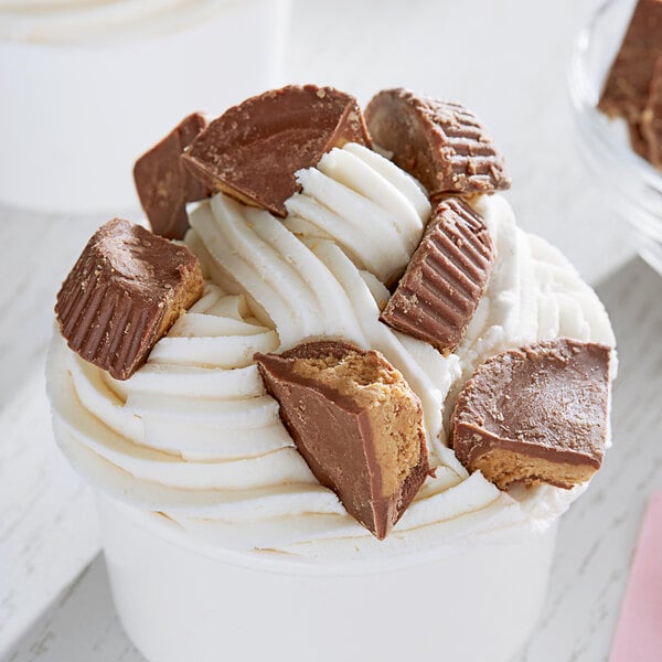 A cup of ice cream with chocolate and peanut butter cups on top.
