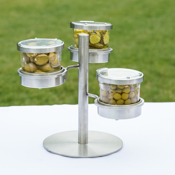 A Cal-Mil stainless steel tiered stand holding three jars with hinged lids.