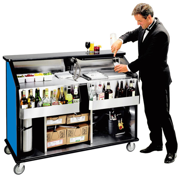 A man in a tuxedo pouring a drink at a Lakeside portable bar with bottles on it.
