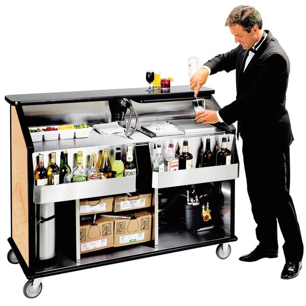 A man in a tuxedo pouring a drink at a Lakeside portable bar with bottles on the counter.