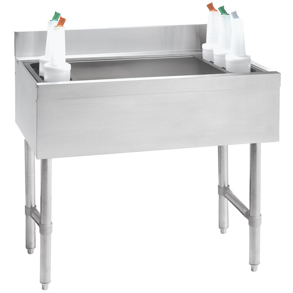 A stainless steel Advance Tabco underbar ice bin with containers on top.