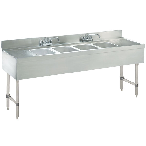 An Advance Tabco stainless steel underbar sink with four compartments and two drainboards.