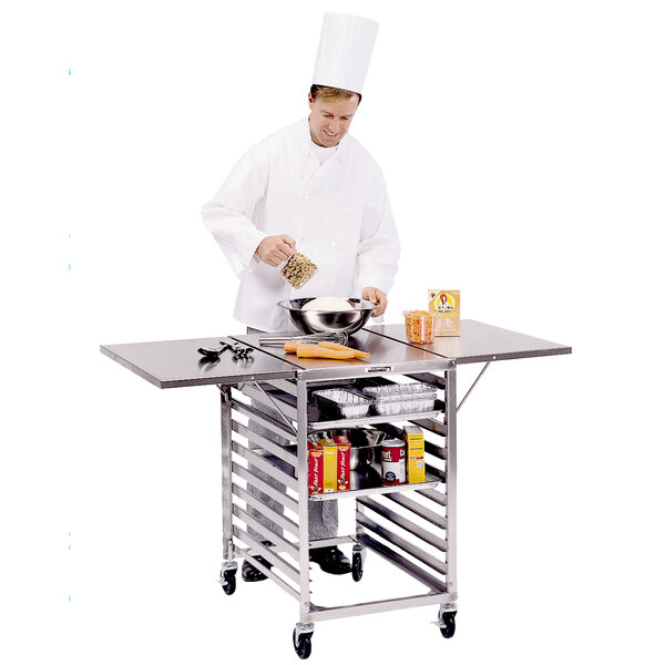 A chef preparing food on a Lakeside stainless steel table with sheet pan storage.