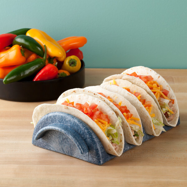 A blue HS Inc. polyethylene taco server holding a row of tacos with vegetables, cheese, and tomatoes.