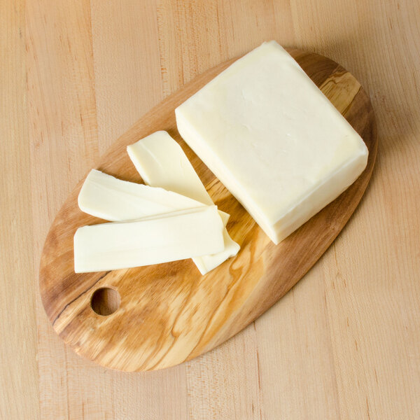 An American Metalcraft oval olive wood serving board with cheese on it.