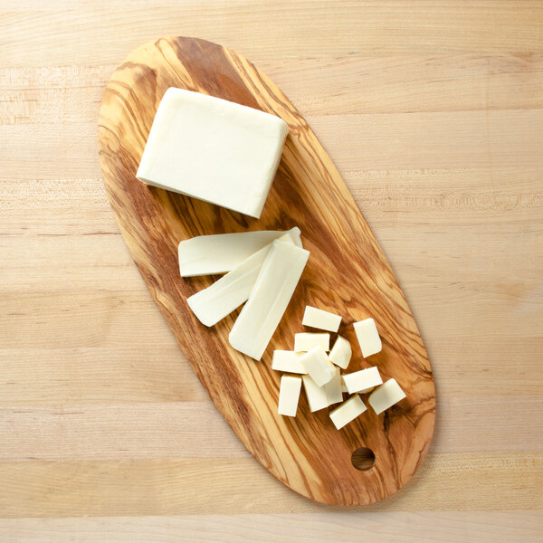 An American Metalcraft oval olive wood serving board with a block of cheese and cubes.