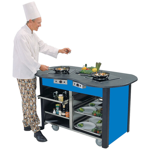 A chef cooking on a stainless steel induction cooking cart with a royal blue laminate finish.