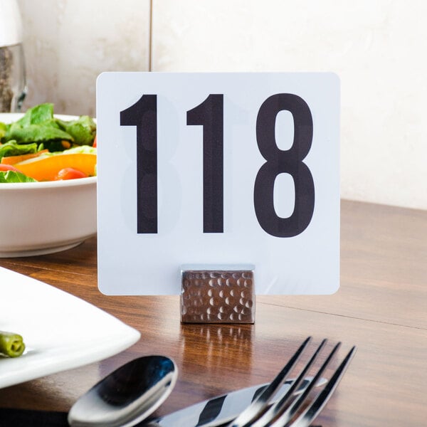 A rectangular silver aluminum card holder with a black number on a plate.