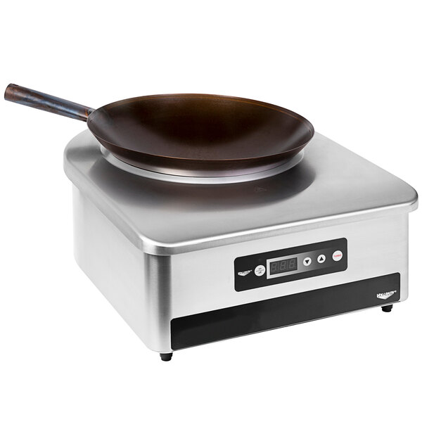 A Vollrath countertop induction wok range with a carbon steel wok pan.