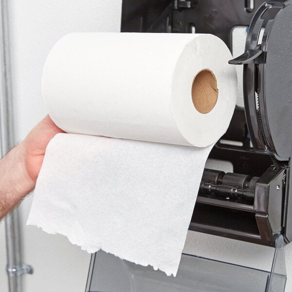 A person's hand holding a Lavex White Hardwound Paper Towel roll.