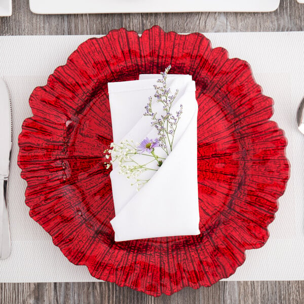 A red Charge It by Jay glass charger plate with a purple flower on it.