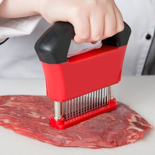 A hand using a Chef Master meat tenderizer with a black and red handle.