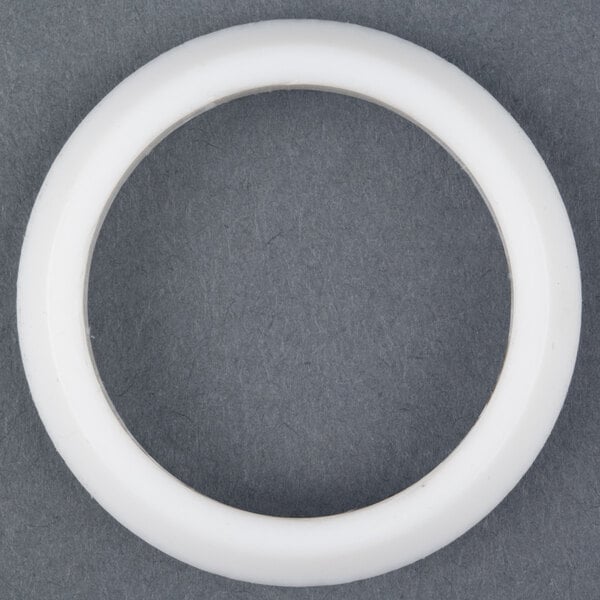 A white plastic circle with a white circle inside on a grey surface.